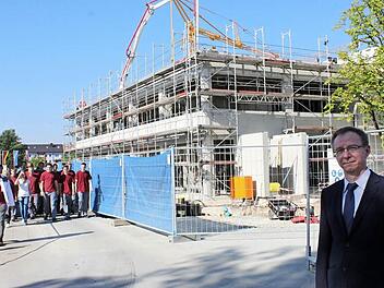 Geschäftsführer Herbert Drechsel vor der im Bau befindlichen neuen Produktionshalle. Mit im Bild der Unternehmensnachwuchs aus der Lehrwerkstatt mit deren Leiter. Foto: Popp