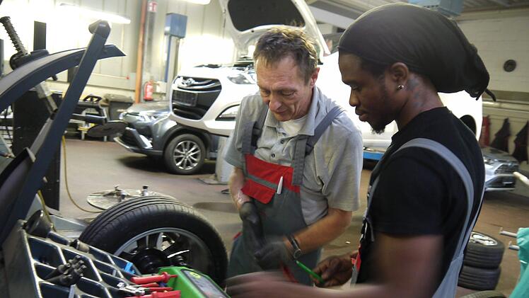 Edgar Luthardt erkl&auml;rt Hilfsarbeiter Chucks Smith das Arbeiten an der Wuchtmaschine. Smith beginnt im September eine Ausbildung zum Kfz-Mechatroniker. Foto: Rebecca Vogt