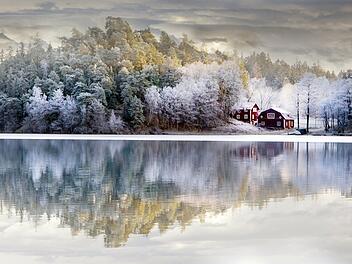 Rural house by a small hill reflected in the water in the early winter L&auml;ndliches Haus in Schweden an einem kleinen H&uuml;gel, das sich im fr&uuml;hen Winter im Wasser spiegelt