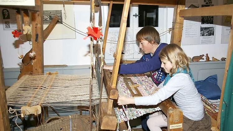 Johanna und ihr Cousin Sebastian erwecken am alten Webstuhl im Heimatmuseum die Geschichte zum Leben. Fotos: Tom Müller