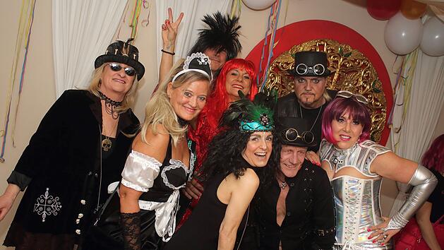 Menschen in fantasievollen Kost&uuml;men feiern ausgelassen Fasching. Bunte Per&uuml;cken, H&uuml;te und Deko schaffen eine fr&ouml;hliche Stimmung auf der Party.