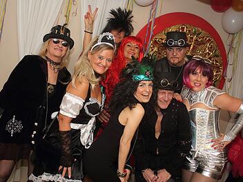 Menschen in fantasievollen Kostümen feiern ausgelassen Fasching. Bunte Perücken, Hüte und Deko schaffen eine fröhliche Stimmung auf der Party.
