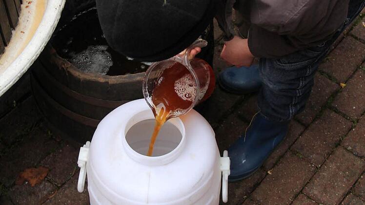 Der frischgepresste Apfelsaft wird in den Vorratsbehälter geschüttet.