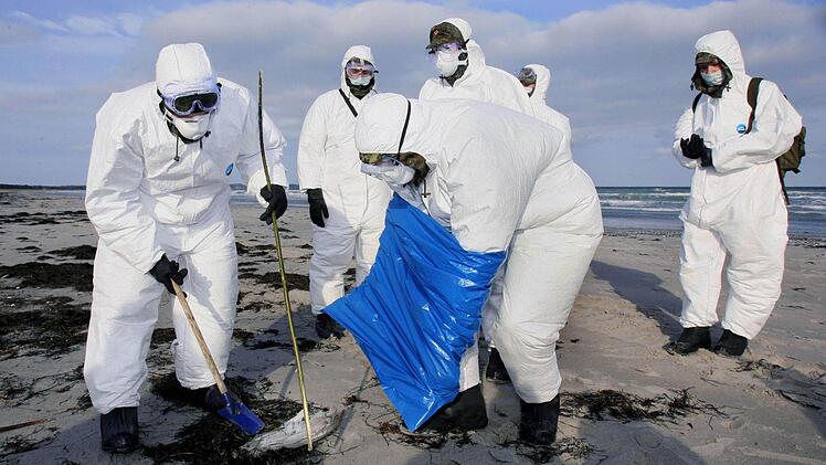 Bundeswehrsoldaten in Schutzanzügen sammelten im Februar 2006 den Flügel eines toten Wasservogels am Strand von Juliusruh auf der Insel Rügen ein. Foto: Jens Büttner, dpa