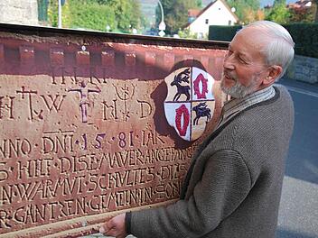 An der Dorfmauer: Alois Tremer bringt die Gedenktafel an, die mit dem Erlös des Orgelpfeifenverkaufs gefertigt wurde. Foto: Norbert Schmitt