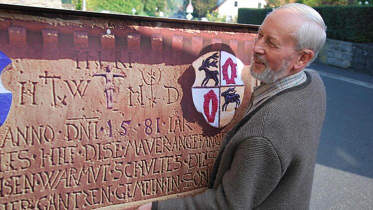 An der Dorfmauer: Alois Tremer bringt die Gedenktafel an, die mit dem Erlös des Orgelpfeifenverkaufs gefertigt wurde. Foto: Norbert Schmitt