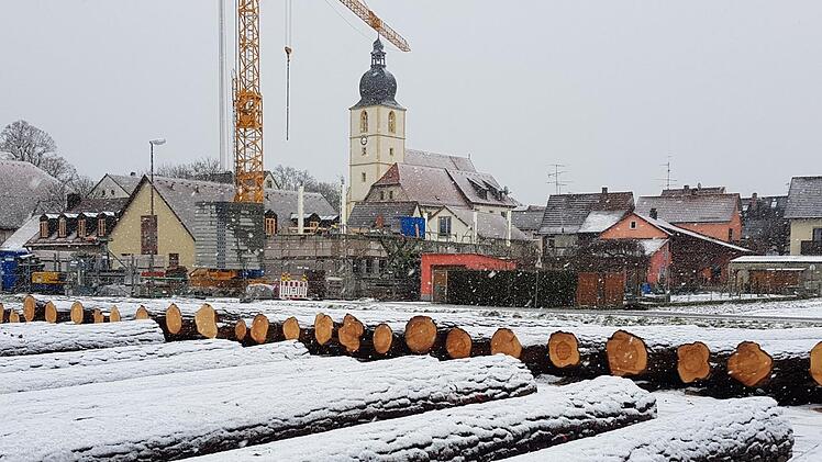 Annähernd die Hälfe des angebotenen Holzes lagert auf dem Wertholzplatz in Rentweinsdorf. Im Hintergrund ist neben der Dreieinigkeitskirche die Baustelle des Kindergartens zu sehen.  Foto: Eckehard Kiesewetter