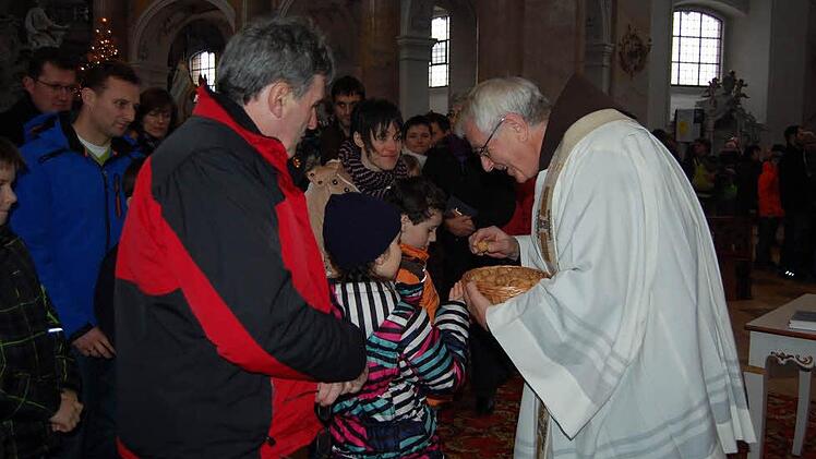Pater Heribert überreicht einem Kind das Symbol des Segnungsgottesdienstes: eine Walnuss. Foto: Andreas Welz