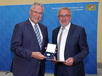 Aus den Händen von Minister Herrmann nimmt Bürgermeister Krämer (r.) seine Medaille entgegen.  Foto: Innenministerium