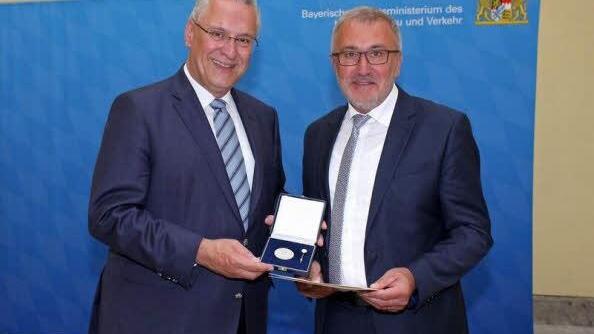 Aus den Händen von Minister Herrmann nimmt Bürgermeister Krämer (r.) seine Medaille entgegen.  Foto: Innenministerium
