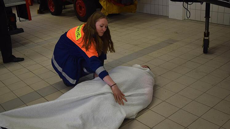 Svenja Apfel demonstriert, wie man einer brennenden Person mit Hilfe einer Rettungsdecke helfen kann.Foto: Daniela Pondelicek
