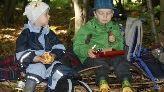 Buddelhose, Hut und Gummistiefel: Waldkindergartenkinder brauchen die richtige Ausrüstung, dann sind sie für alle Abenteuer gewappnet. Auf dem Waldsofa schmeckt Tim (rechts) und Fabian die Brotzeit besonders gut. Foto: sw