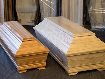 Ein extragroßer Sarg (r) liegt im Lager eines Sarg-Herstellers in Nürnberg neben einem Sarg in Standard-Größe. Foto: Daniel Karmann/dpa