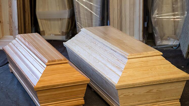 Ein extragroßer Sarg (r) liegt im Lager eines Sarg-Herstellers in Nürnberg neben einem Sarg in Standard-Größe. Foto: Daniel Karmann/dpa