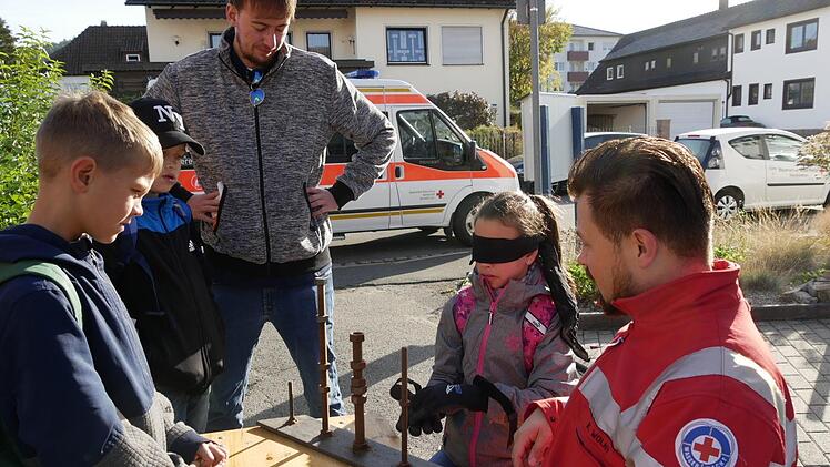 Paula probiert aus, wie das geht, wenn ein Wasserwachtler wie  Kamil Wolny (rechts) als Rettungstaucher  unter Wasser Schrauben zu packen  kriegen muss. Julian, Joel und Alexander Herr von der Jugendpflege schauen  dabei interessiert zu. Ohne Handschuhe und mit den Augen alles sehen, das  ist schon wesentlich einfacher.    Foto: Manja von Nida