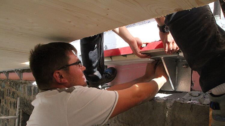 Junior-Chef Jens Reugels befestigt zusammen mit einem Kollegen einen Träger für den Balkon. Foto: Ulrike Müller