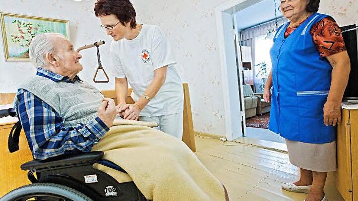 Eine Frau versorgt ihren pflegebedürftigen Mann - das ist häufig der Normalfall. In diesem Fall leistet eine Pflegeschwester vom Deutschen Roten Kreuz professionelle Unterstützung.  Foto: Archiv/epd