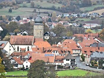 Blick auf Pfarrweisach mit der Pfarrkirche St. Kilian in der Mitte. Im Hintergrund lugen die Häuser von Junkersdorf hervor, eingebettet in baum- und heckenreiche Höhenzüge.