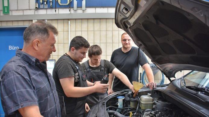 Karl-Otto Behrmann (links) und sein Sohn Dominic (hinten rechts) beobachten ihren Lehrling Amjad, der unter Anleitung des Gesellen Domenic Hültner an einem Fahrzeug  Servo-Öl nachfüllt. Hanns Friedrich