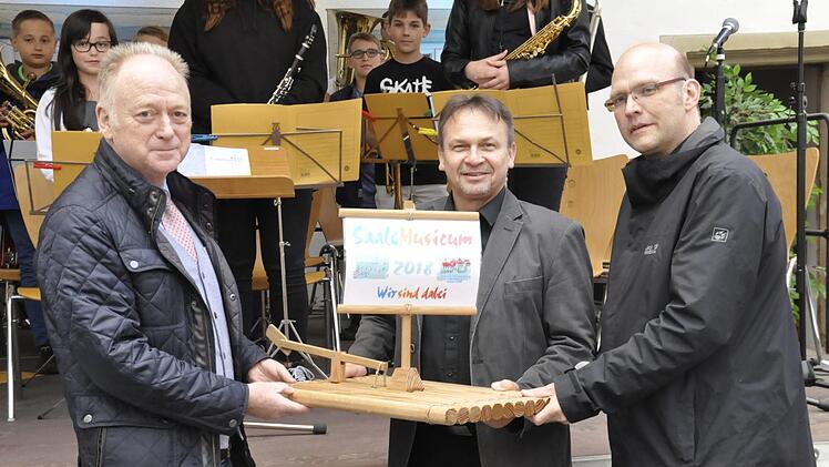 Kuno Holzheimer (Mitte), der musikalische Leiter der Bayerischen Musikakademie Hammelburg überreichte das Floss des "SaaleMusicum" an Bürgermeister Helmut Blank (links) und den Musikschulleiter Thomas Reuß. Foto: Peter Klopf