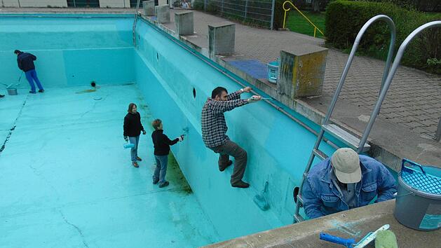 Die Helfer klettern im Becken herum, um auch alle Stellen zu streichen. Foto: Petra Malbrich
