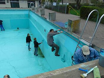Die Helfer klettern im Becken herum, um auch alle Stellen zu streichen. Foto: Petra Malbrich