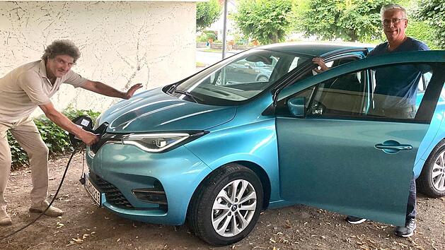 Ihr ganzer Stolz: Armin Knauf und Herbert Seidel beim Tanken ihres E-Autos, das von der Gemeinschaft genutzt werden kann.