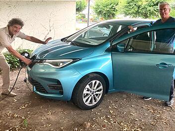 Ihr ganzer Stolz: Armin Knauf und Herbert Seidel beim Tanken ihres E-Autos, das von der Gemeinschaft genutzt werden kann.