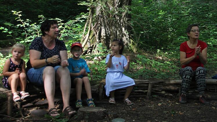 Birgit Kestel (links) und Martina Zwosta (rechts) singen mit den Kindern auf dem selbst erbauten Waldsofa im Festungswald. Foto: Magdalena Kestel