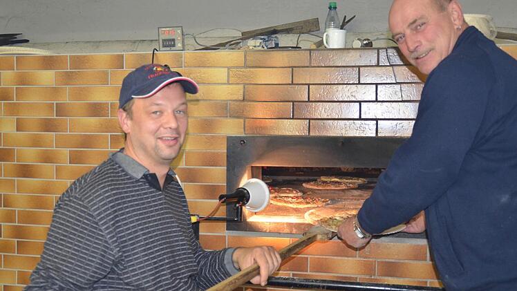 Im Backhaus sind Mario Metz (l.) und Rudi Vorndran an einem von zwei Backöfen beschäftigt. Die Plootze werden mit der "Schierschüssel" hineingeschoben und wieder herausgeholt. Foto: Kathrin Kupka-Hahn