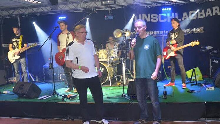 Schützenmeister Frank Zapf dankt Bürgermeister Hans Pietz (links) für sein 20-jähriges Engagement als musikalischer und technischer Organisator der Friedersdorfer Rocknacht. Im Hintergrund, die Band Unschlagbar.  Foto: K.- H. Hofmann