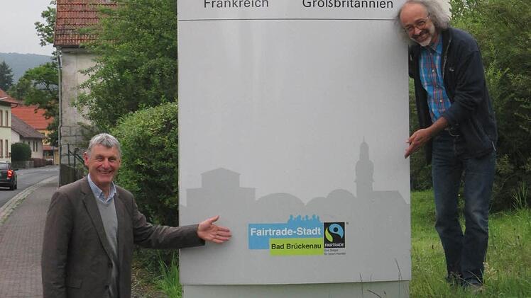 Stolz auf die erste Fairtrade-Stadt der Rhön: Stadtrat Jürgen Pfister (links) und Dirk Hönerlage von der Eine-Welt-Gruppe an einem der Pylonen, die auf das Siegel aufmerksam machen. Foto: Fairtrade-Steuerungsgruppe