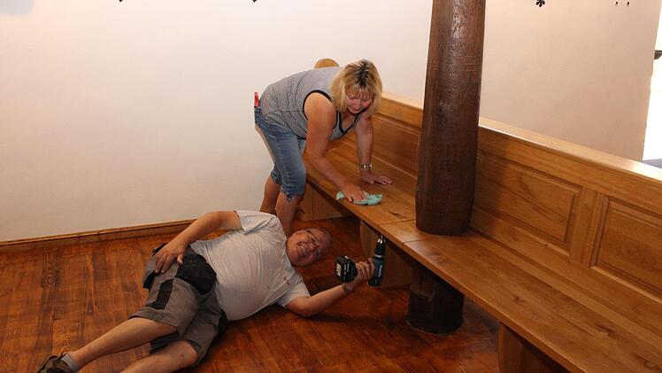 Pfarrgemeinderatsvorsitzender Richard Simmet schraubt die Bänke fest. Petra Wichert reinigt inzwischen die Bänke vom Staub.