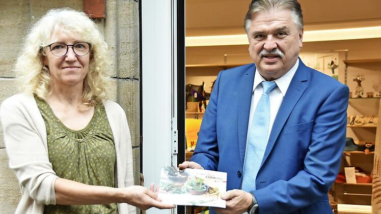 Landrat Klaus Peter Söllner überreichte das neue Klima-Kochbuch "Fair-Cooking" an Marion Meyer, Leiterin des Weltladens.