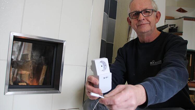 Ofenbauer Hans-Werner Denzler zeigt einen Fensterschutzschalter. Die Dunstabzugshaube hängt am Stecker. Der kleine Magnetschalter kommt an das Fenster. Durch einen Stromimpuls auf den Steckdosenempfänger weiß die Haube: Achtung, Fenster ist geschlossen.  Foto: Christian Bauriedel