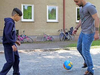Ahmet Al-naib (27) spielt mit Haje (12) vor der Gemeinschaftsunterkunft Fußball. Foto: Alexander Hartmann