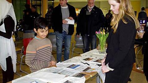 Ein syrischer Junge betrachtet die Präsentation "Gründe für die Flucht", die Lena Heinlein (rechts) mit Niklas Greiner und Veronika Klemm erarbeitet hat.