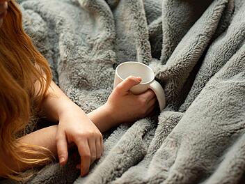 Eine Decke und ein Tee halten wohlig warm und sparen Energie.
