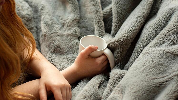 Eine Decke und ein Tee halten wohlig warm und sparen Energie.