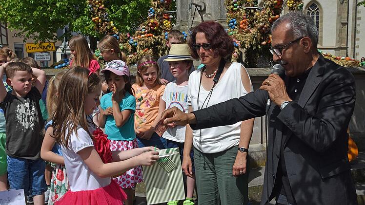 Die Schüler der Grundschule Haßfurt Schulhaus Sylbach sammelten nach ihrem begeisternden Chorauftritt auf dem Marktplatz in Haßfurt für die Aktion Tschernobyl Kinder. Hachem Farmand, Berater des Aktionskreises Haßfurt Aktiv (rechts), war der erste Spender und erhielt eine von den Kindern bemalte Karte mit einem Frühlingsgedicht.Ulrike Langer