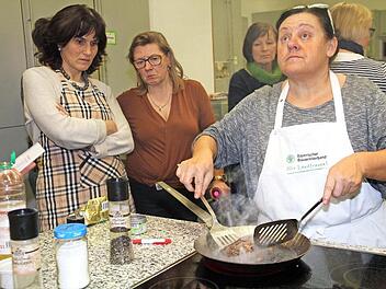 Monika Gerner (r.) wirft einen prüfenden Blick zur Uhr zur Stirnseite der Lehrküche. Nach drei Minuten wendet sie das Rumpsteak. Foto: Gerda Völk