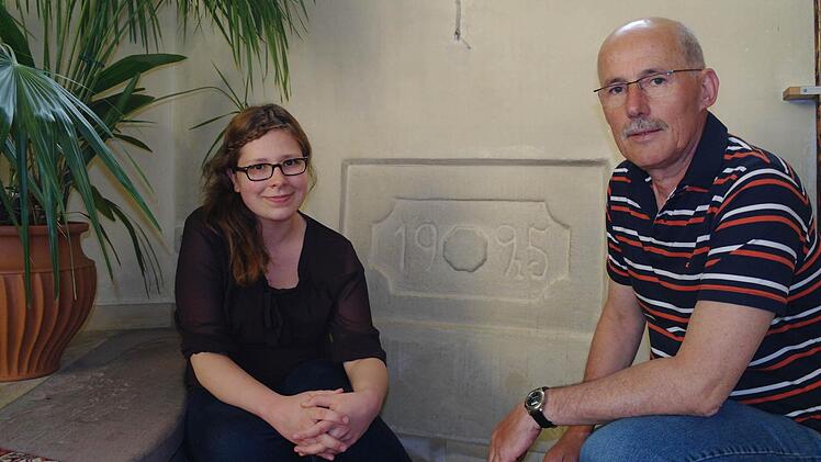 Maren Ebert und Rudolf Klug sitzen vor dem Grundstein der Speicherzer Kirche, der das Jahr 1925 zeigt. Foto: Stephanie Elm