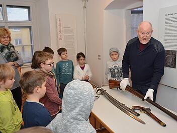 Kreisheimatpfleger Christian Neugebauer zeigte die Bewaffnung und Ausrüstung, die im 30-jährigen Krieg zum Einsatz kam. Die Kinder und Lehrerin Andrea Foth schauen sich die Gegenstände fasziniert an. Foto: Björn Hein