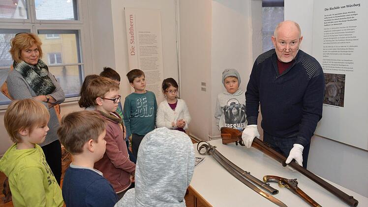 Kreisheimatpfleger Christian Neugebauer zeigte die Bewaffnung und Ausrüstung, die im 30-jährigen Krieg zum Einsatz kam. Die Kinder und Lehrerin Andrea Foth schauen sich die Gegenstände fasziniert an. Foto: Björn Hein