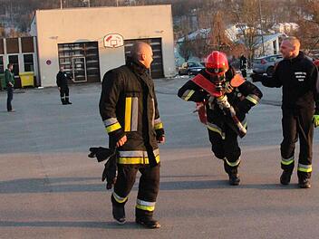 Je weiter die B-Schläuche gezogen werden, desto wärmer und schwerer werden sie. Sebastian Sauer (links) und Daniel Fritz (rechts) feuern hier Mike Korten an, der das Atemschutzgerät trägt und die Schläuche schleppt. Foto: Simone Bastian