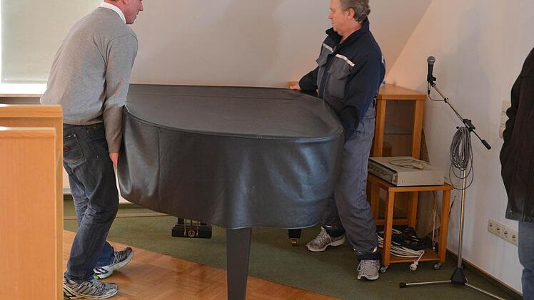 Chistian und Heunz Haußner testen zunächst einmal das Gewicht und hieven das Instrument auf Decken, damit der Parkettboden nicht zerkratzt wird.