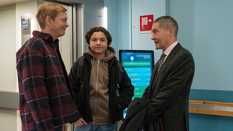 Dr. Rolf Kaminski (Udo Schenk, rechts) freut sich &uuml;ber den &Uuml;berraschungsbesuch von seinem Sohn Fabian Althaus (Daniel Krauss, links) und Enkel Jack (Franz Hagn) zum Weihnachtsfest.