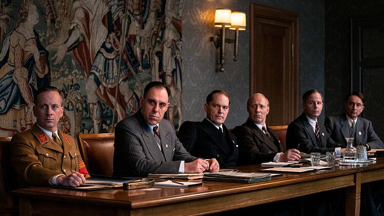 Von links: Dr. Gerhard Klopfer (Fabian Busch), Friedrich Wilhelm Kritzinger (Thomas Loibl), Dr. Wilhelm Stuckart (Godehard Giese), Martin Luther (Simon Schwarz), Erich Neumann (Matthias Bundschuh) und Dr. Roland Freisler (Arnd Klawitter) beraten.