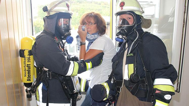 Susanne Ender wird von den Atemschutzgeräteträgerinnen Ramona Hackl und Sabine Rudolph in Sicherheit gebracht. Foto: Michael Stelzner