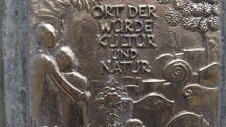 Eine Bronzeplakette am Ebenhäuser Waldfriedhof weist auf die Auszeichnung des Bayerischen Landesverbandes für Gartenbau und Landschaftspflege hin. Foto: Stefan Geiger